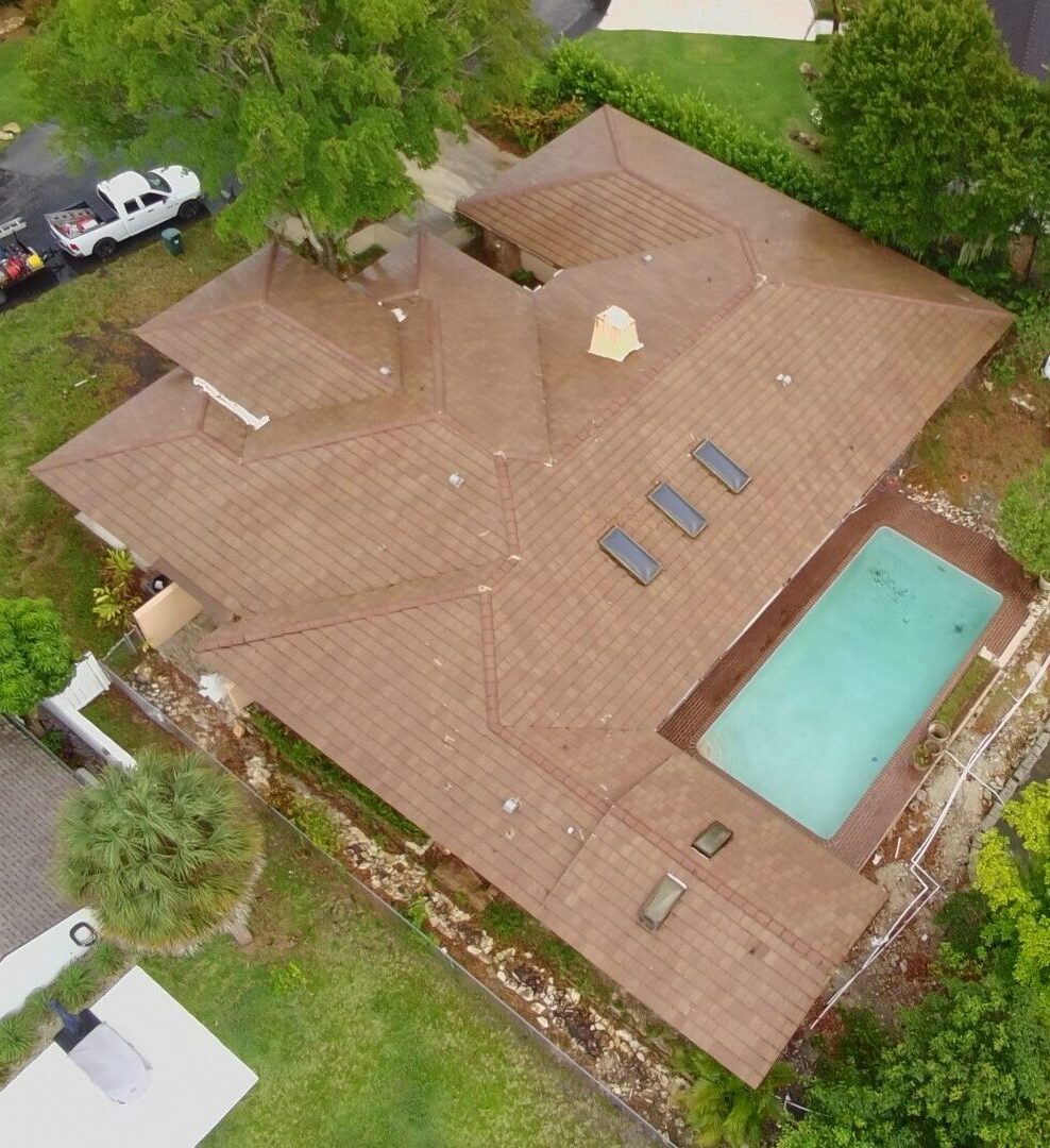 Flat concrete tile roof being soft washed in Parkland FL